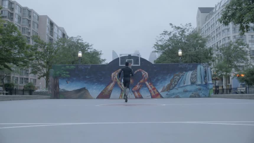 Black bearded man runs in the basketball field on in the city a cloudy day