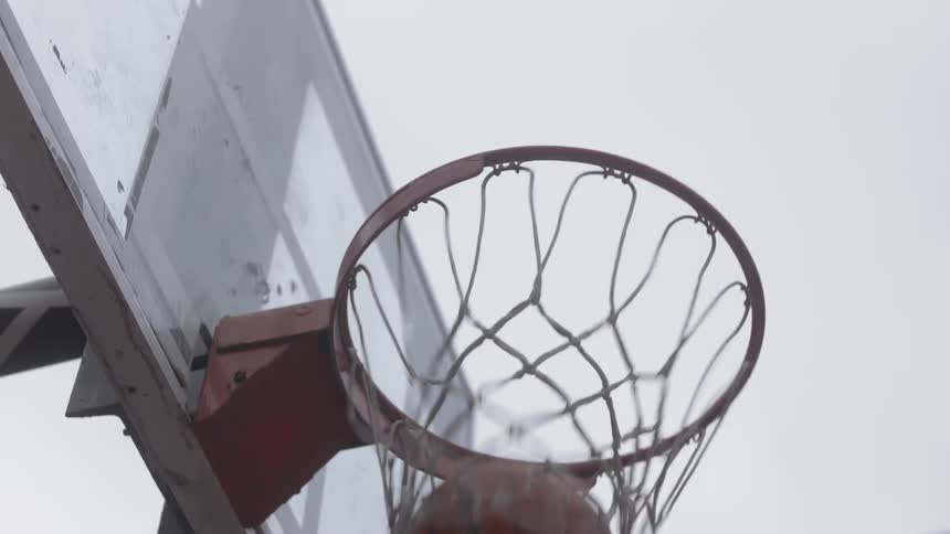 The camera looks up as a person dunks a basketball through a hoop