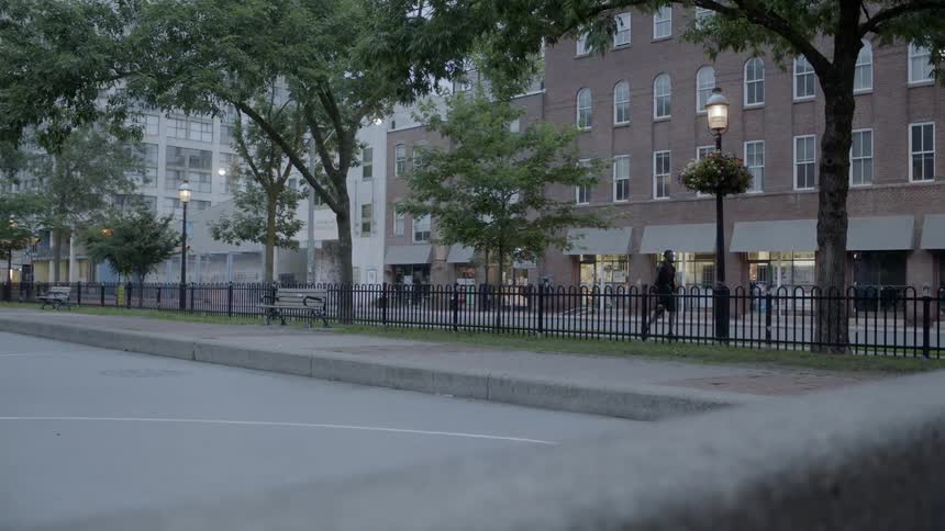 A man carrying a basketball walks along a city street