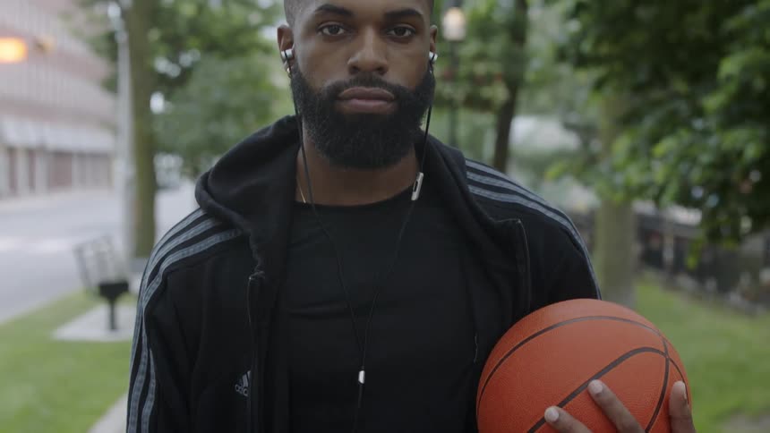 A man on the sidewalk holding a basketball