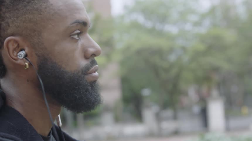 Man walks next to a street with earbuds in