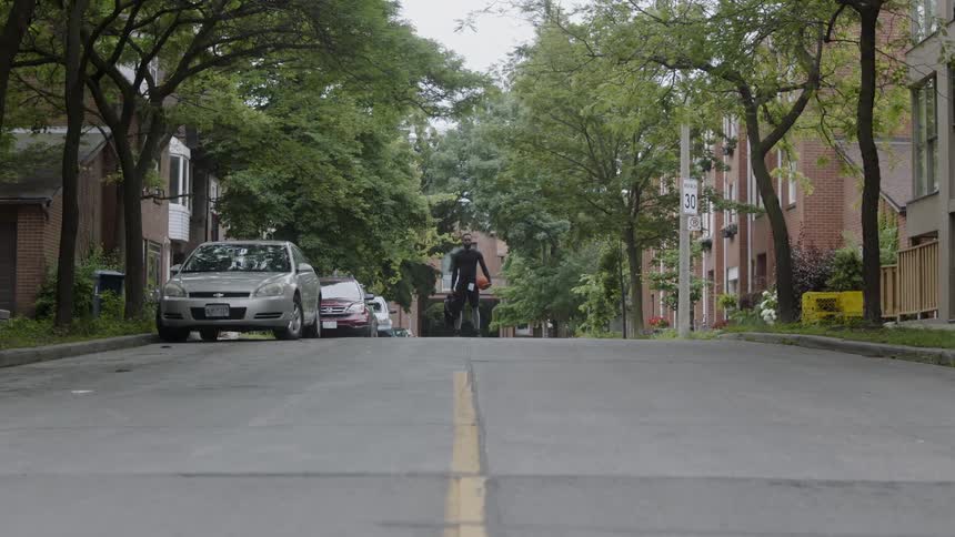 Man standing in a street holding a basketball