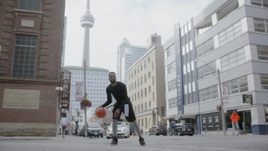 Man dribbles a basketball on a city street