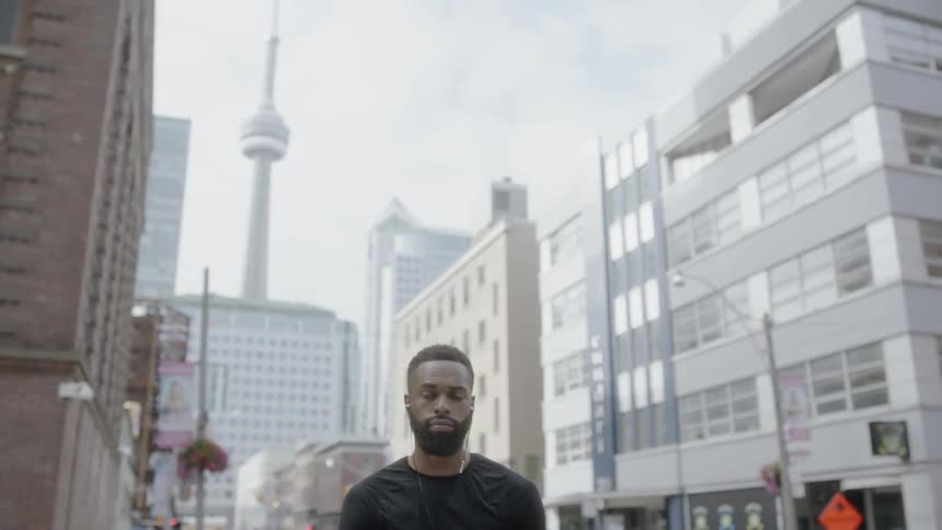 A man standing on a sidewalk listening to music