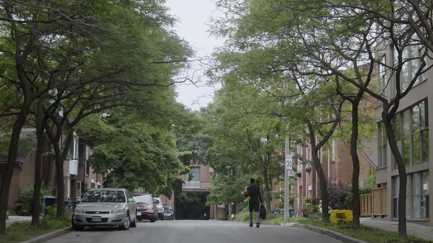 Man walks down a street carrying a basketball