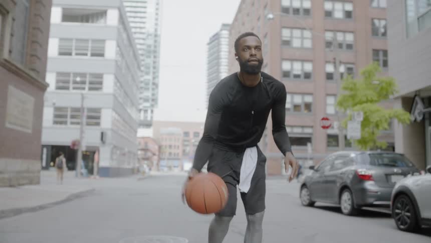 Man dribbles a basketball on the street of a city