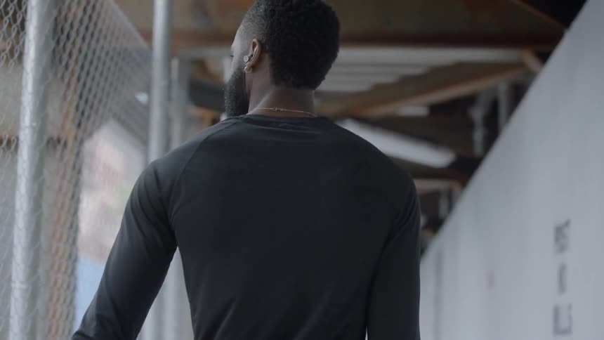 A man walks along a construction walkway carrying a basketball