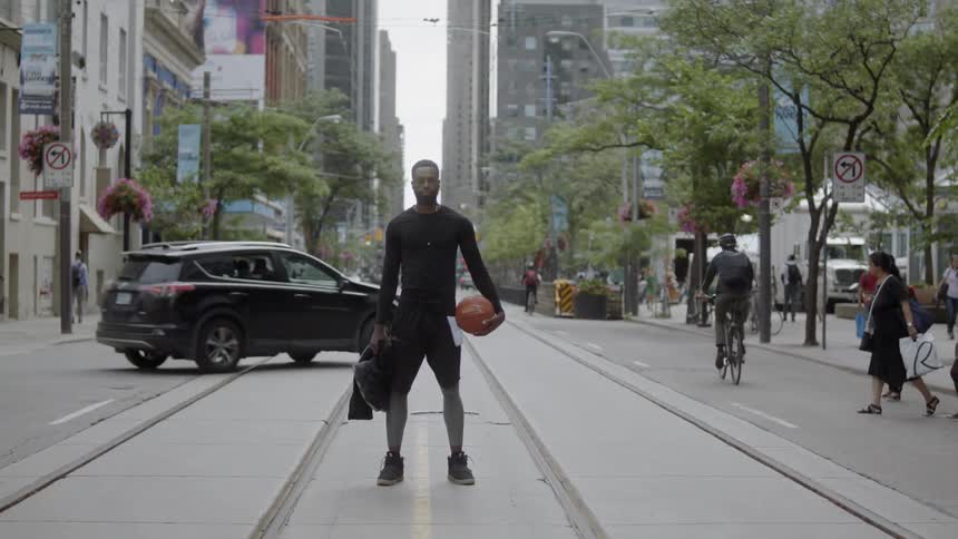 A man standing in the middle of the street holding a basketball