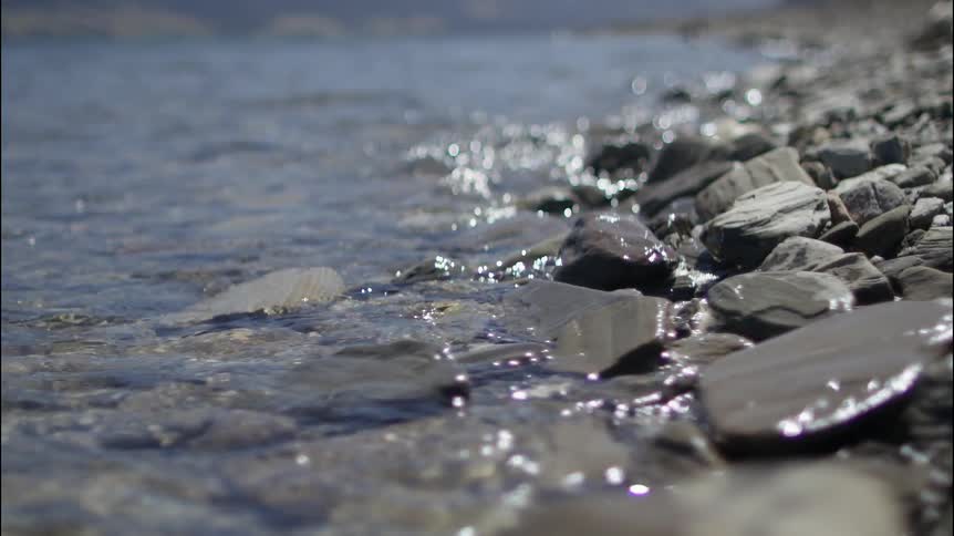 Water gently splashing ashore on a rocky beach area