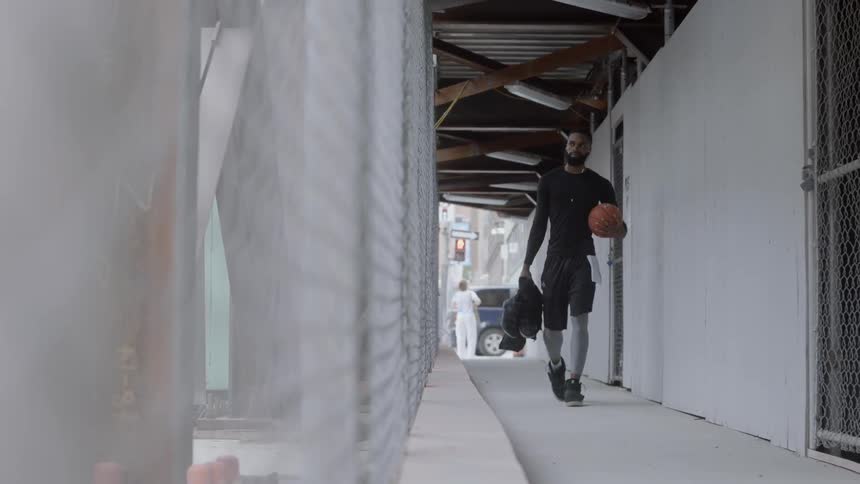 Black man walking through an outside apartment corridor in the city