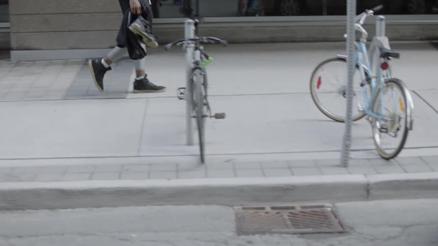 A man walks down the sidewalk holding shoes and a basketball