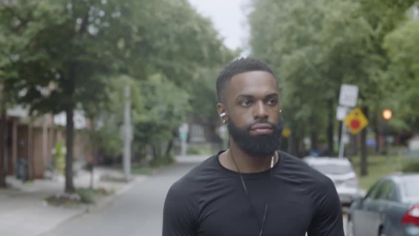 A man walks down the street listening to music on earbuds