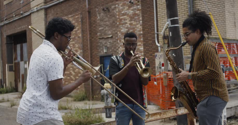 A saxophonist trumpet player and trombonist play music together in an urban environment