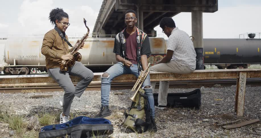 Young black men resting at railroad holding musical instruments