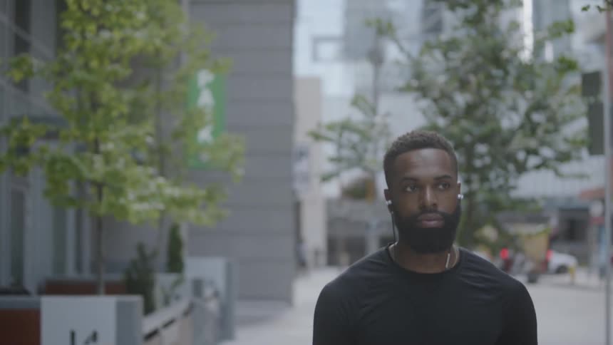 Man walking down a city street while listening to music on headphones