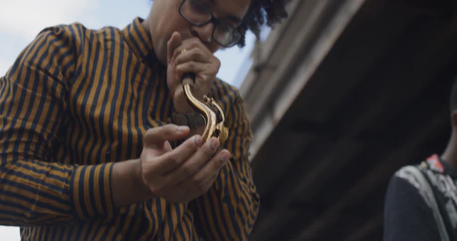 Man blows into saxophone mouthpiece and neck joint