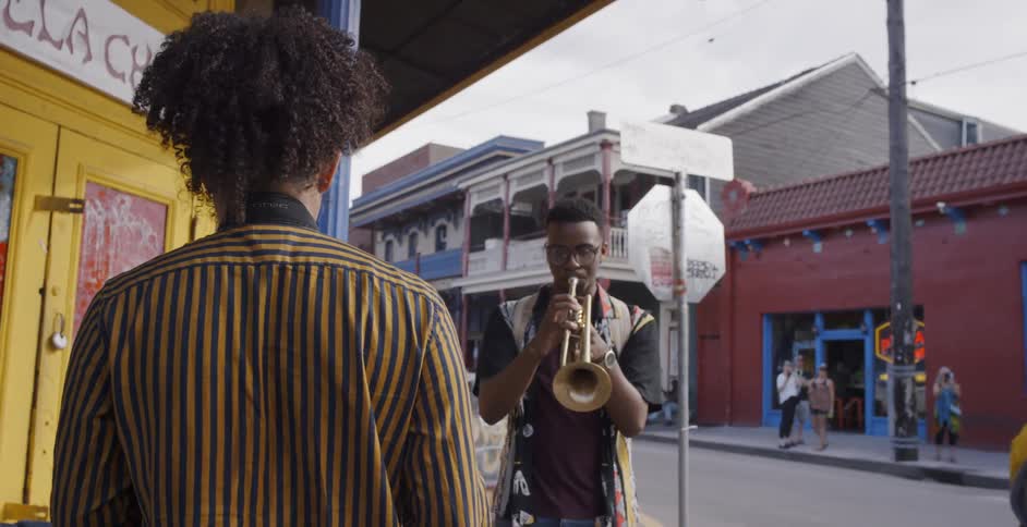 Two people are playing music on a street with a saxophone and a trumpet