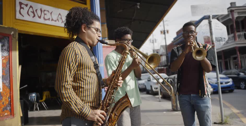 Musicians play brass instruments outside of a storefront