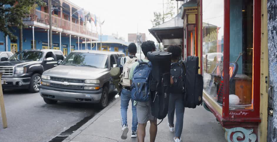 Three people walking down a city street carrying large backpacks