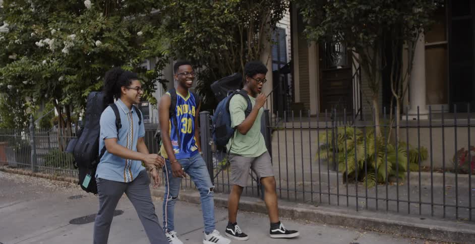 Three boys walk down a neighborhood sidewalk