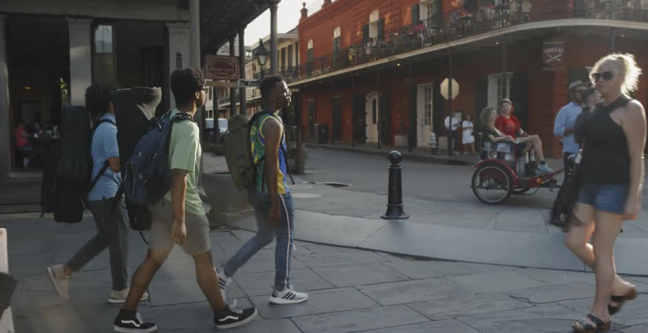 Three black man walk down the street wearing backpacks in the daytime