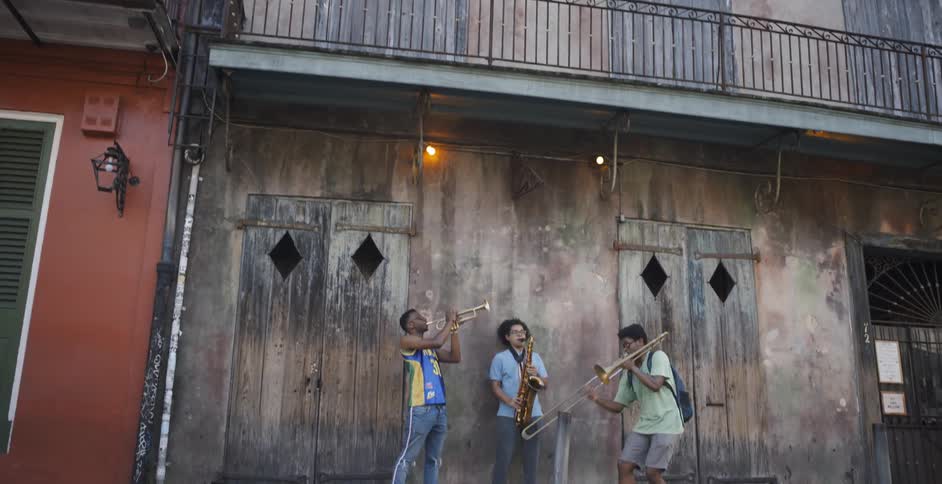 Three young black street musicians perform outside old city building