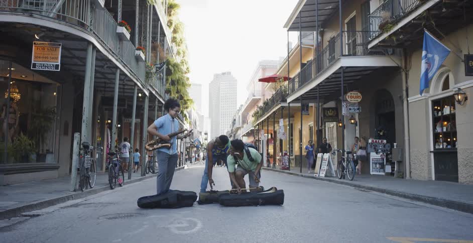 Three people remove musical instruments from the cases in the middle of the road