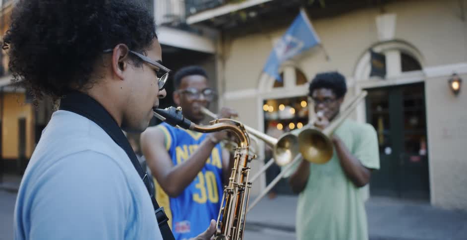 Three young people play brass instruments in the street