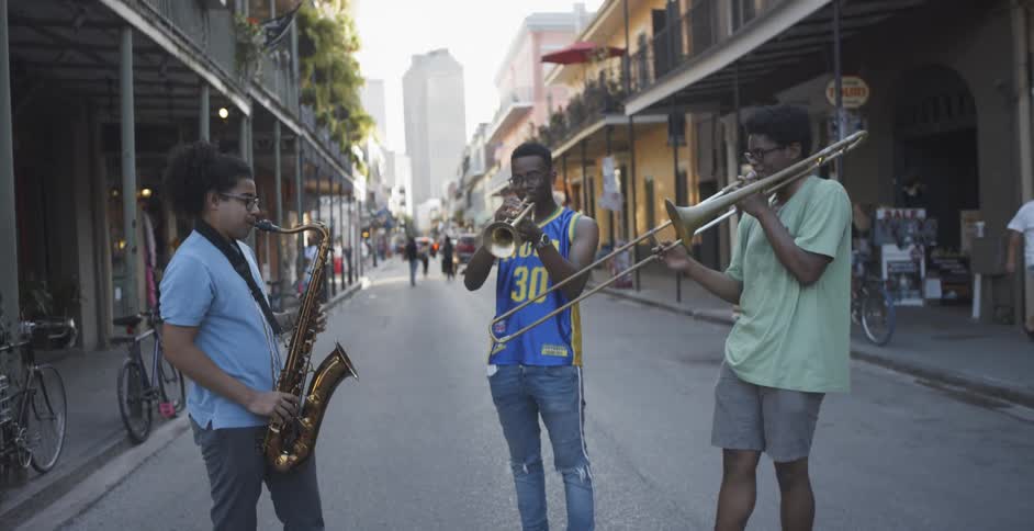 Three young black musicians perform on city street