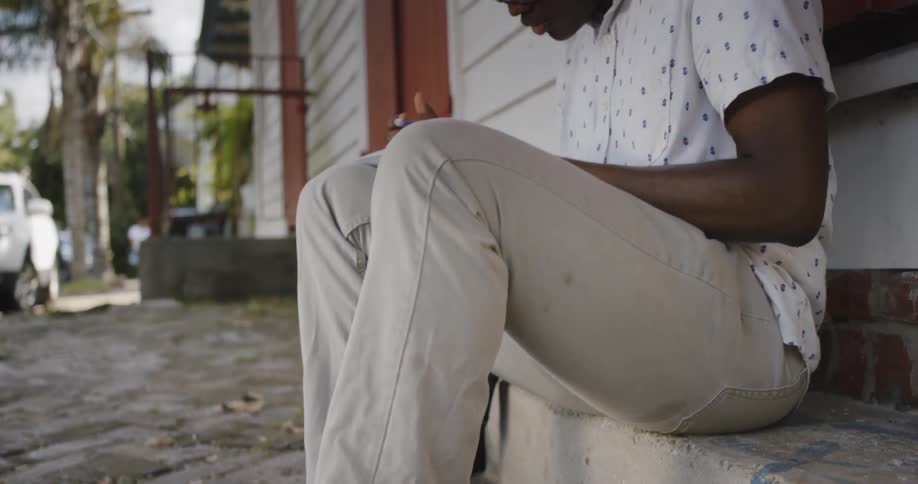 A young black man sits tapping his foot while writing in a book