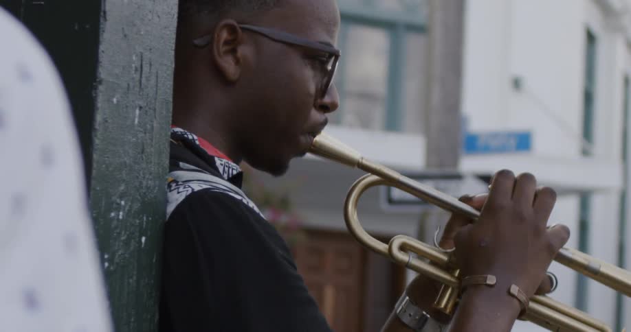 Black boy wearing glasses plays saxophone outdoors in the daytime
