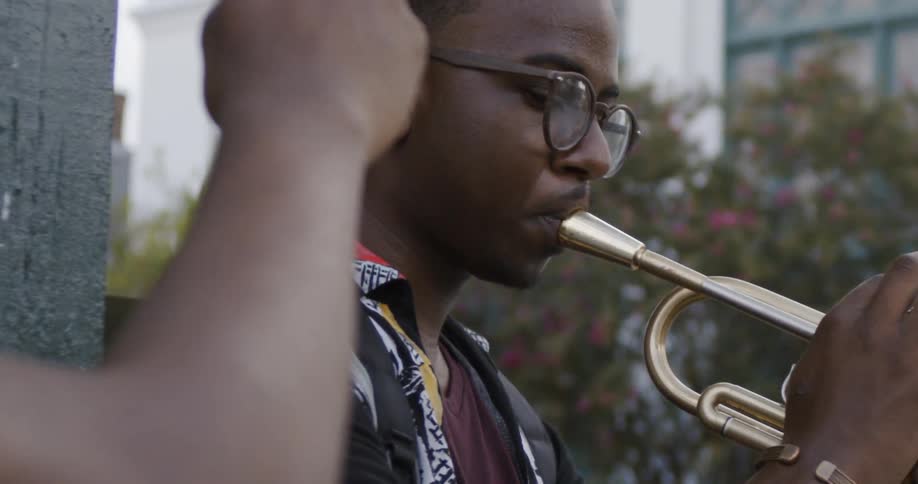 Black male wearing glasses playing the trumpet