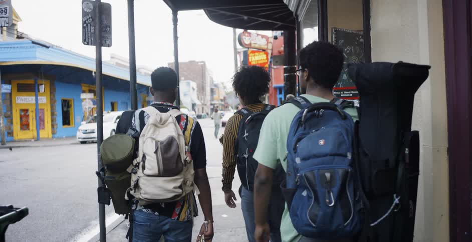 Three men walk through the city with band instruments