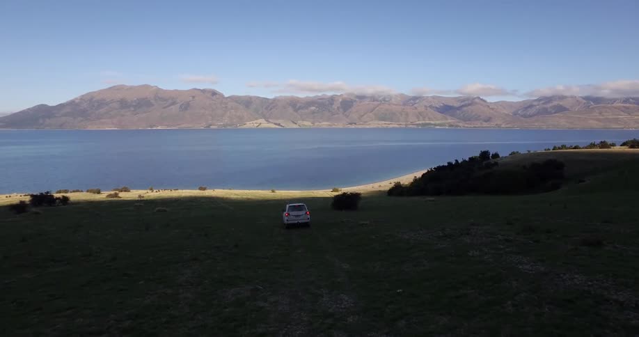 Car driving down a grassy hill towards the ocean
