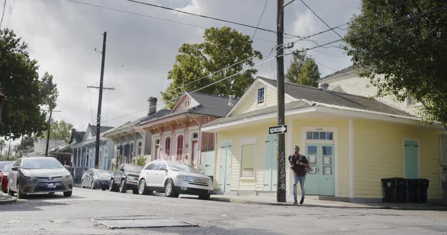 A young black man exits a building and jogs across an intersection