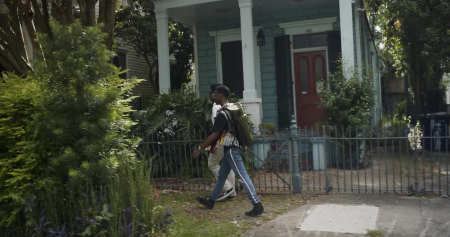 Two black boys walk in the neighborhood in the daytime