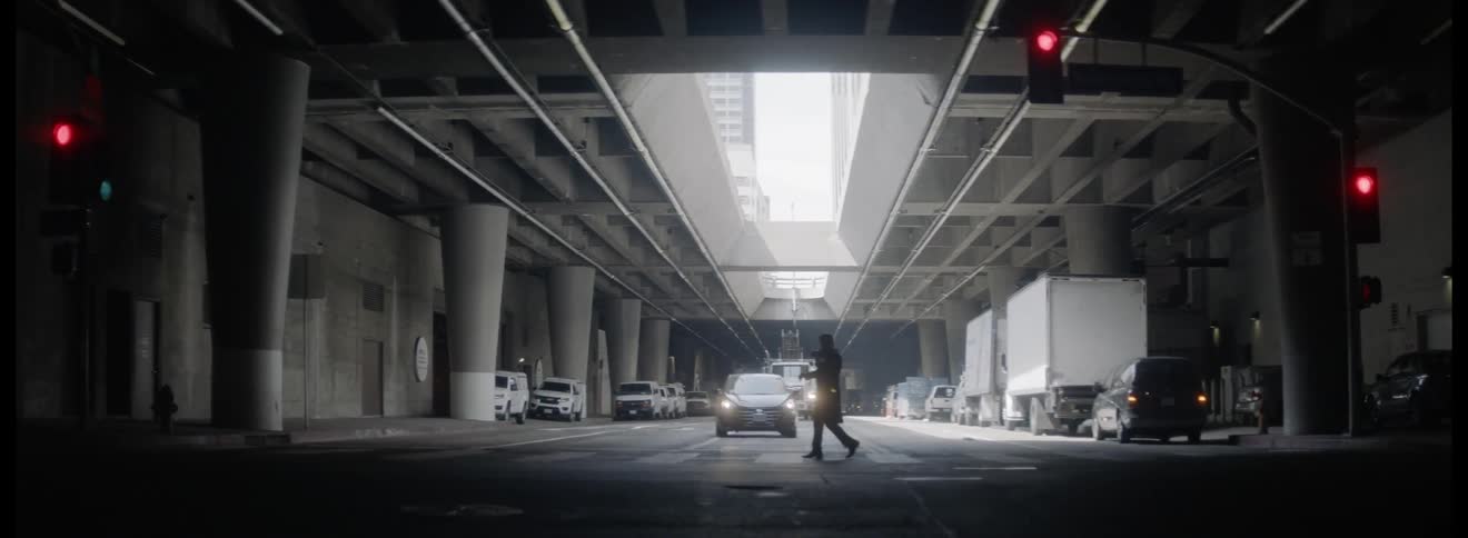 A person crosses the crosswalk under a bridge