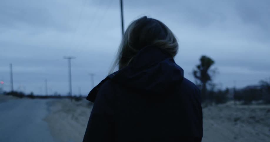 Woman walking down a rural road at nightfall