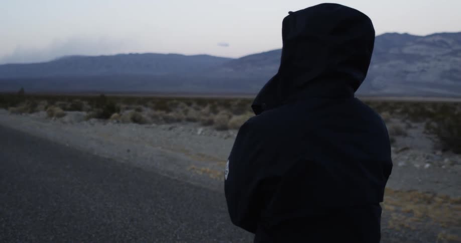 Person in a jacket standing in the road in the middle of nowhere