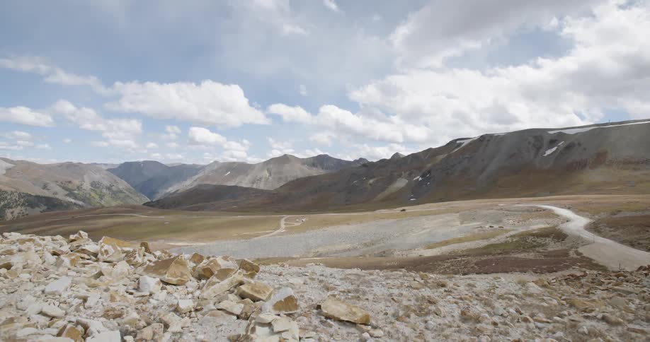 Car drives along a range of mountains on a cloudy day