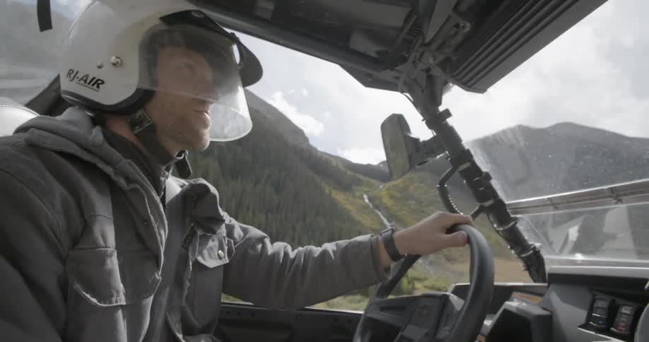 A man wearing a helmet driving a vehicle over rough terrain