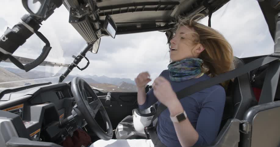 Woman in all terrain vehicle buckles seat belt and adjusts hair