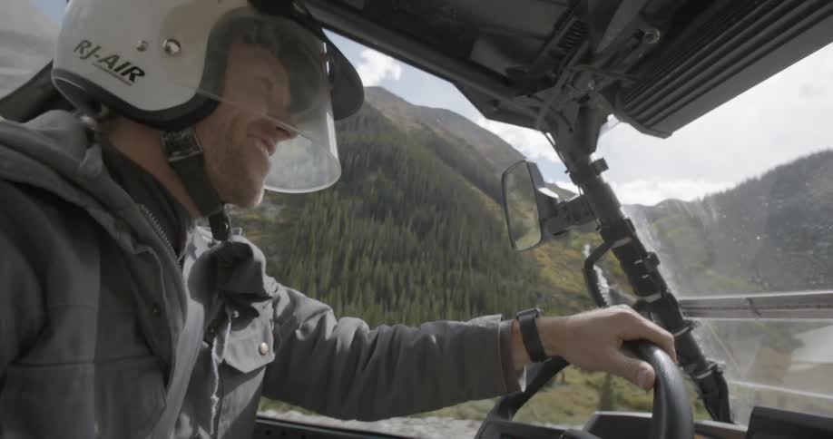 Man driving all terrain vehicle smiles and flashes peace sign
