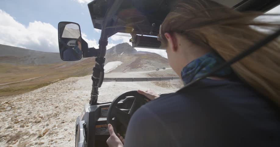 A woman starts a motor buggy on a windy desert path