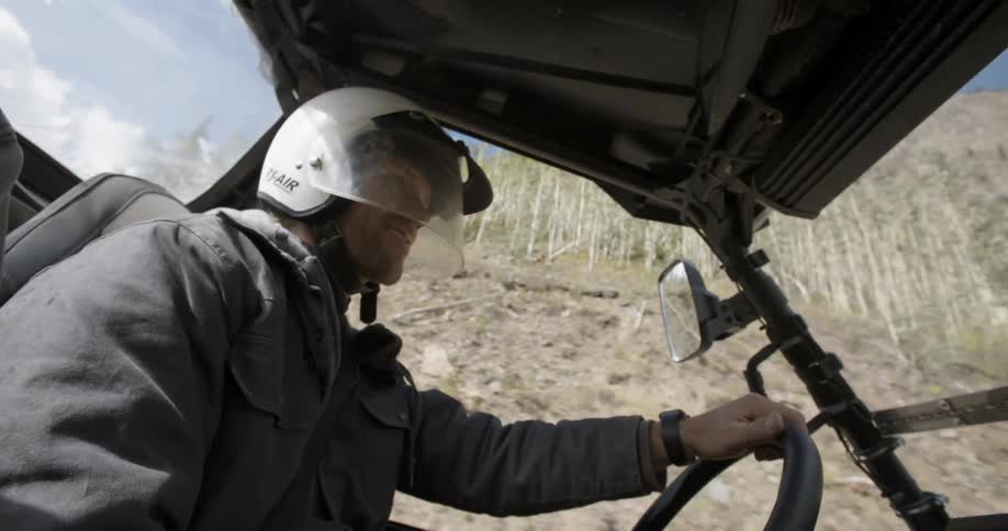 A white man drives a buggy through a forest