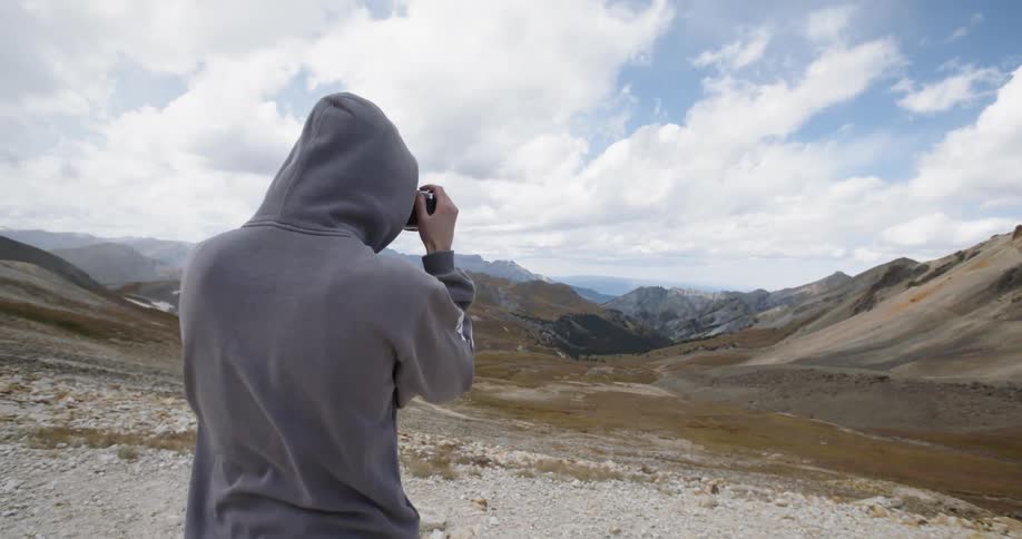 Man wearing hoodie takes picture of horizon on a cloudy day in daytime