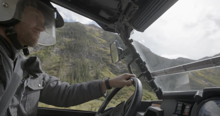 Man in helmet driving atv through mountains