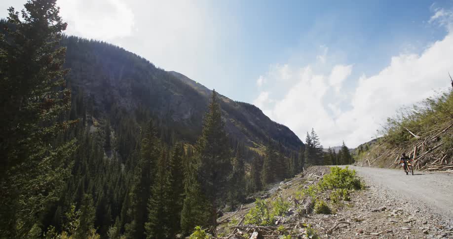 Two motorcyclists ride their bikes down a mountain path