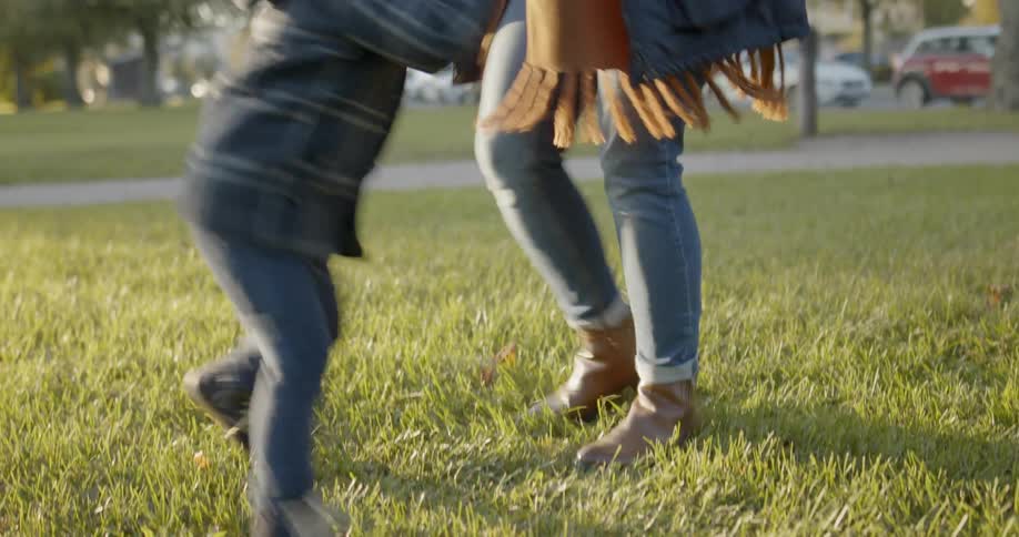 A woman in a coat and head covering spins a little girl around in a circle