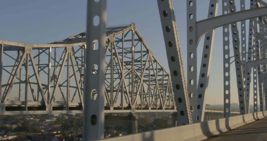 Cars drive across a large bridge over a dense city